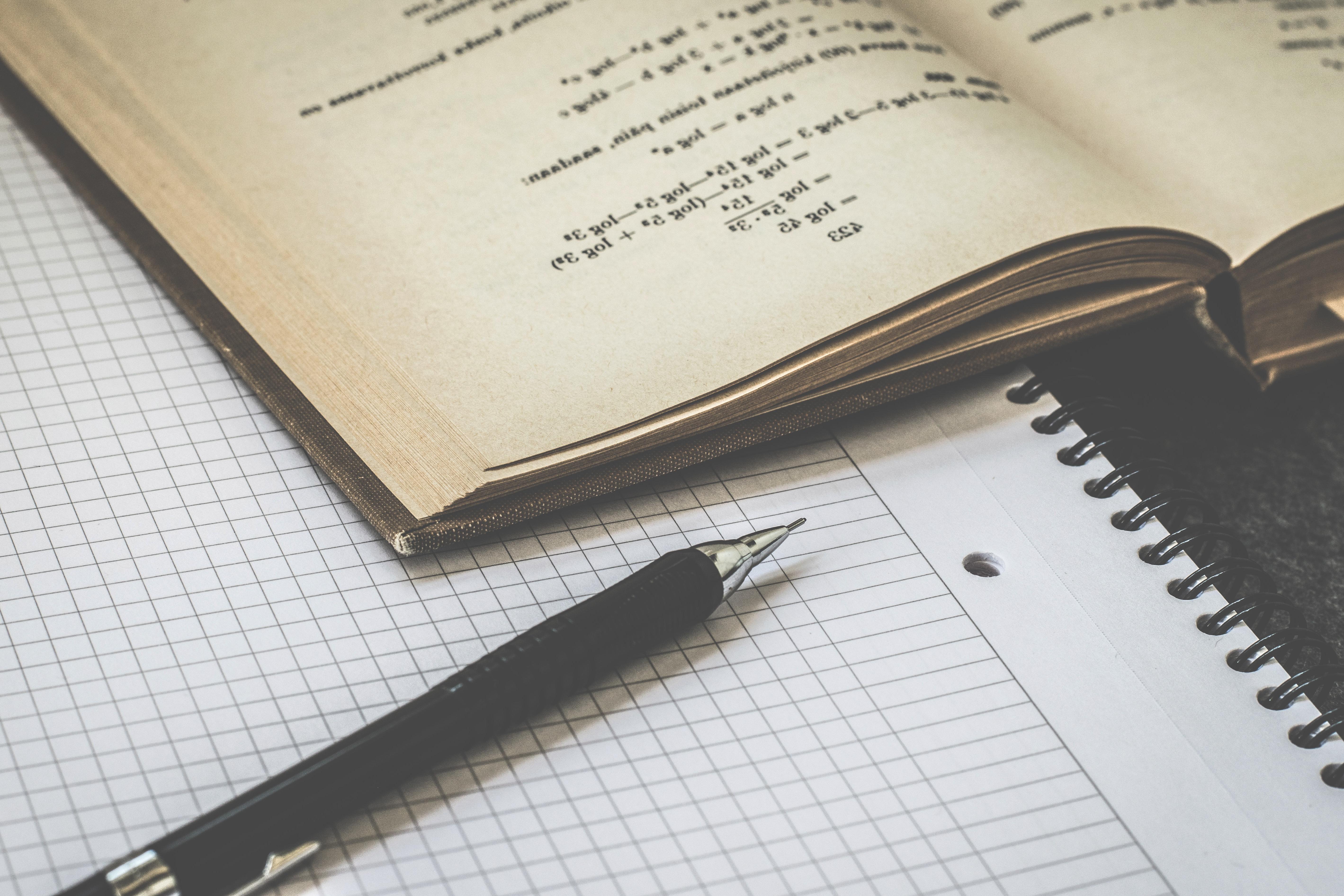 A textbook and a pen resting on top of some graph paper