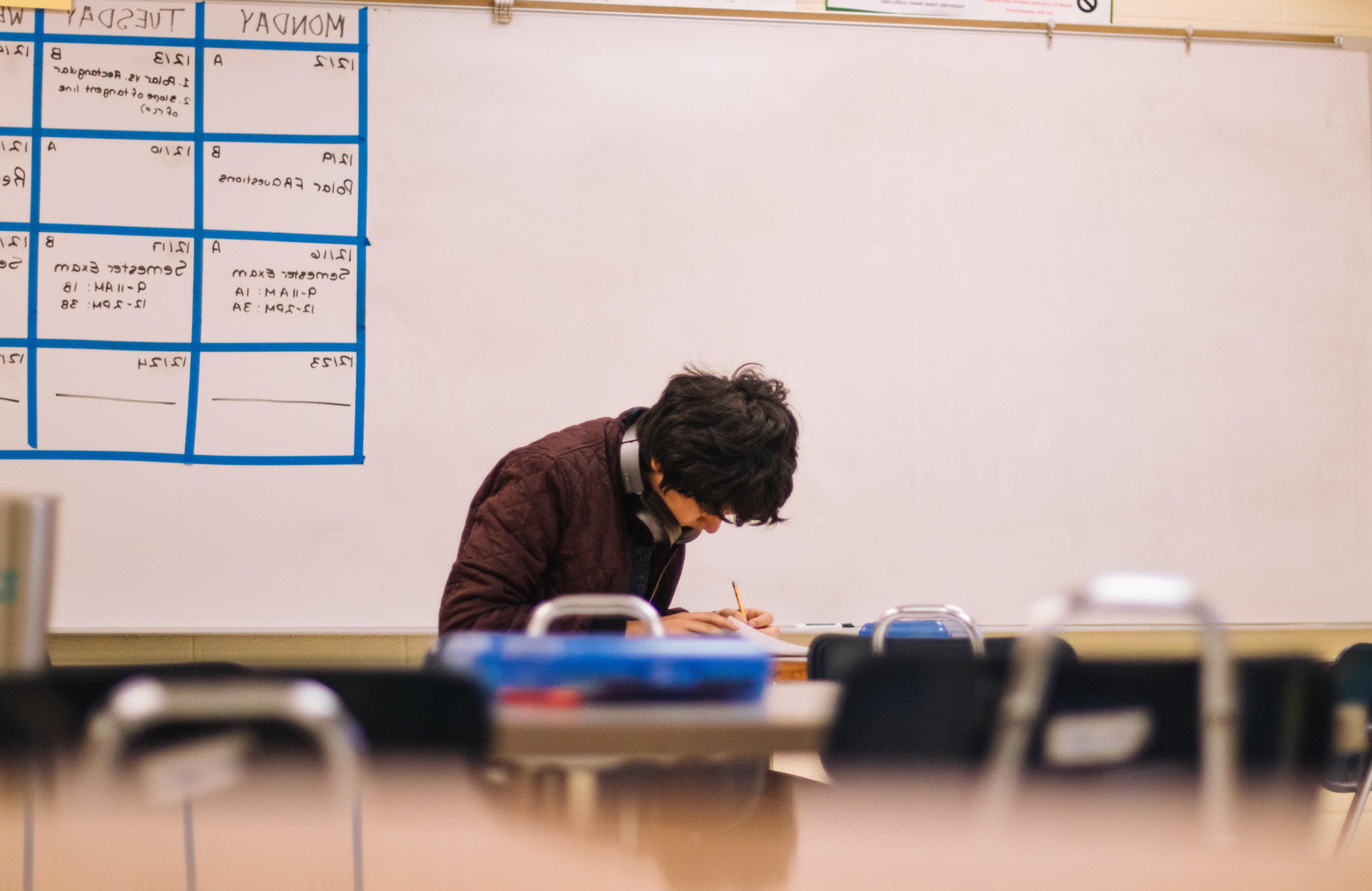 A male student sitting by himself at a desk